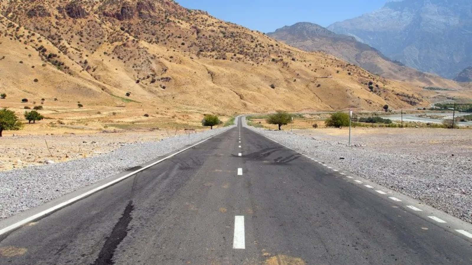 絲綢之路古道壯麗風景 壁紙 — 一條筆直的瀝青公路在晴朗的藍天下穿過乾旱的山脈伸向遠方。