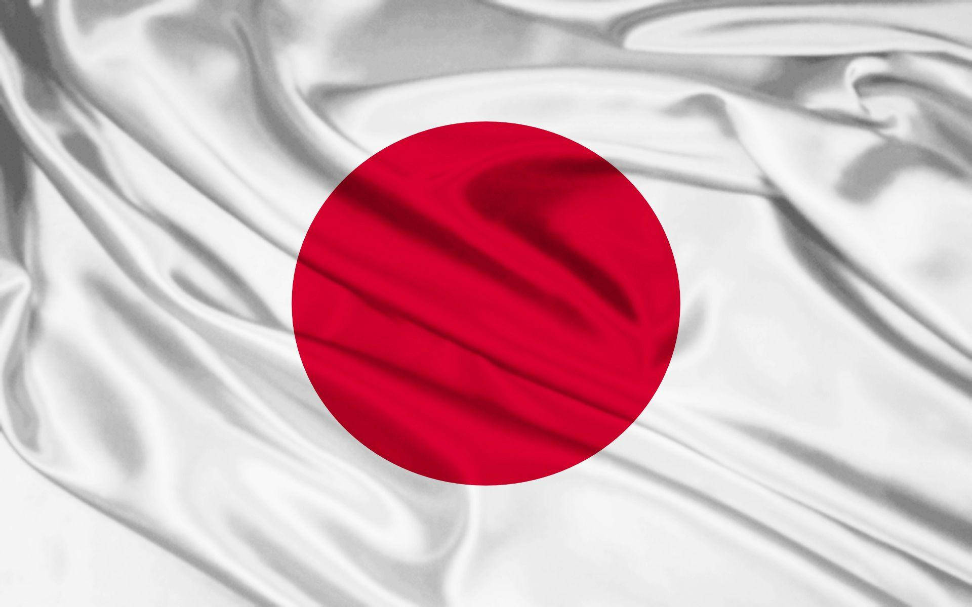 絲質日本國旗 壁紙 — 日本國旗的特寫，白色絲綢質感的布料中央有一個紅色圓圈，呈現自然的褶皺和高光。