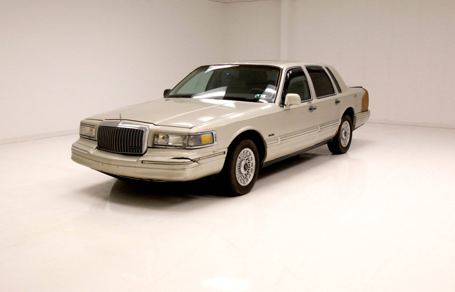 經典 1996 林肯 Town Car 全貌 壁紙 — 一輛米色1990年代林肯城市轎車在極簡白色工作室中展示，地板具有反射效果。
