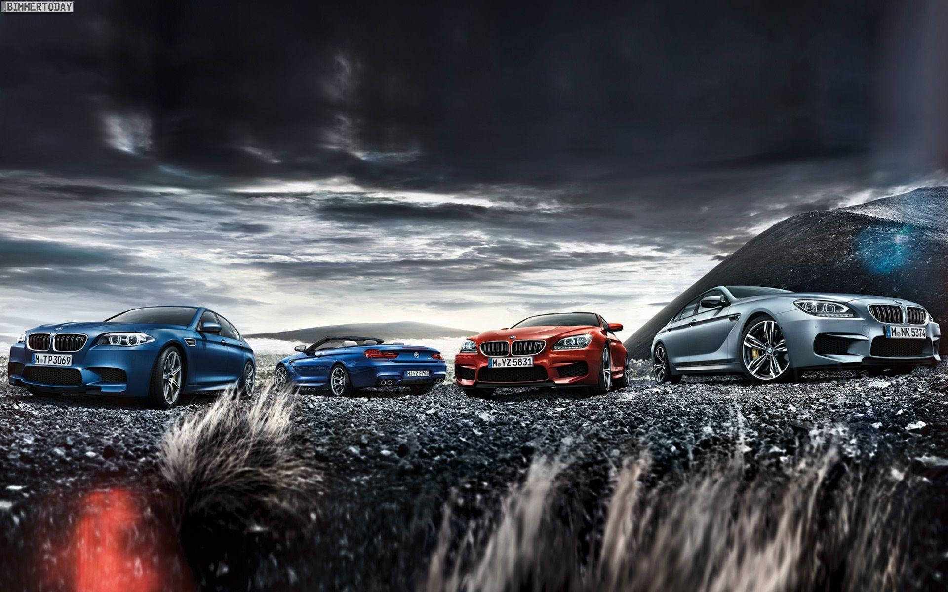 經典 BMW M 系列車款 壁紙 — 四輛高性能BMW跑車，藍色、紅色和銀色，在暴風雨的天空下戲劇性地站在火山礫石平原上。