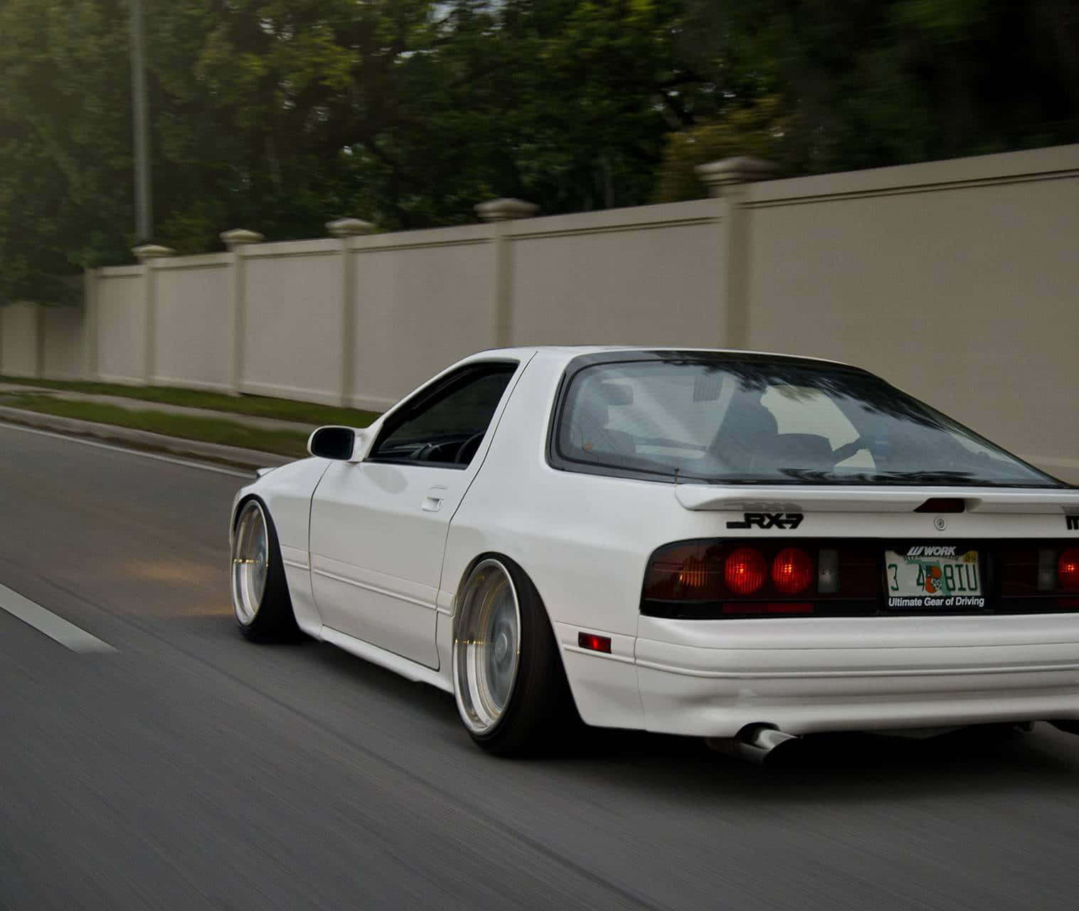 白色RX-7跑車在日落時分行駛在郊區街道上。