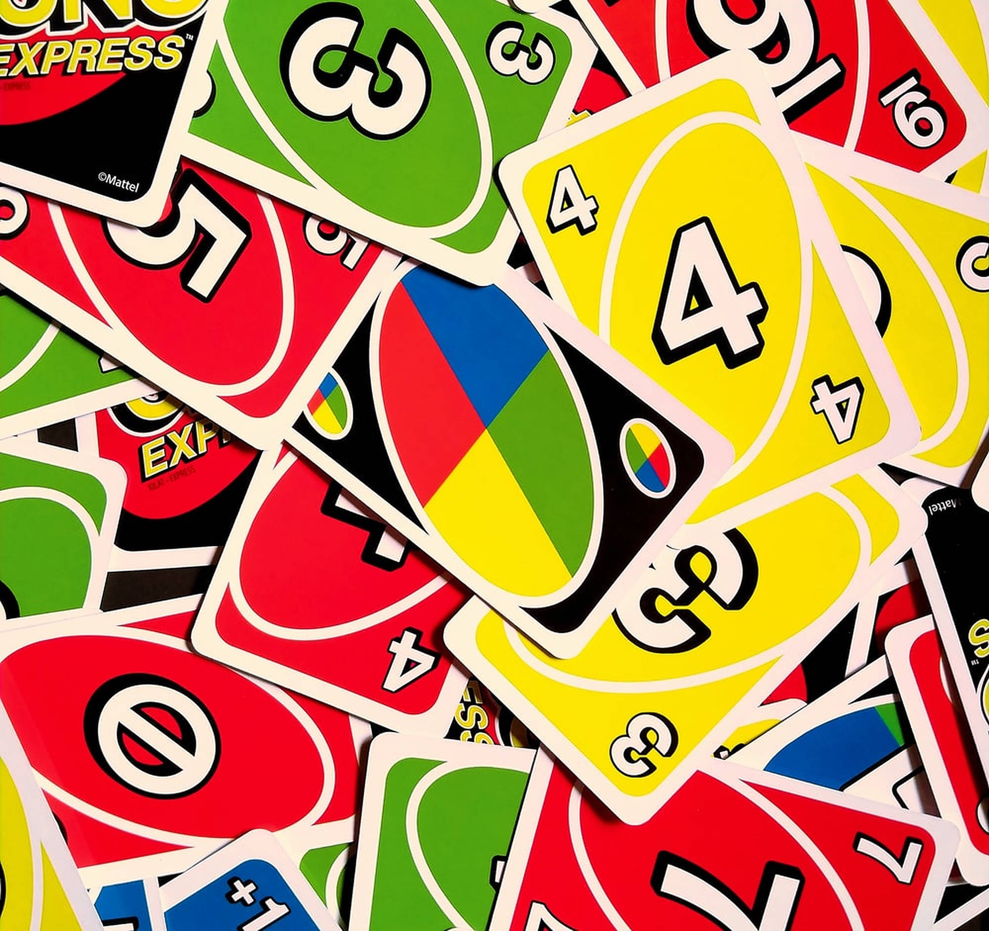 經典 Uno 卡牌遊戲 壁紙 — 一堆色彩繽紛混亂的 Uno Express 卡牌，有紅色、綠色、黃色和藍色，帶有粗體數字和符號。