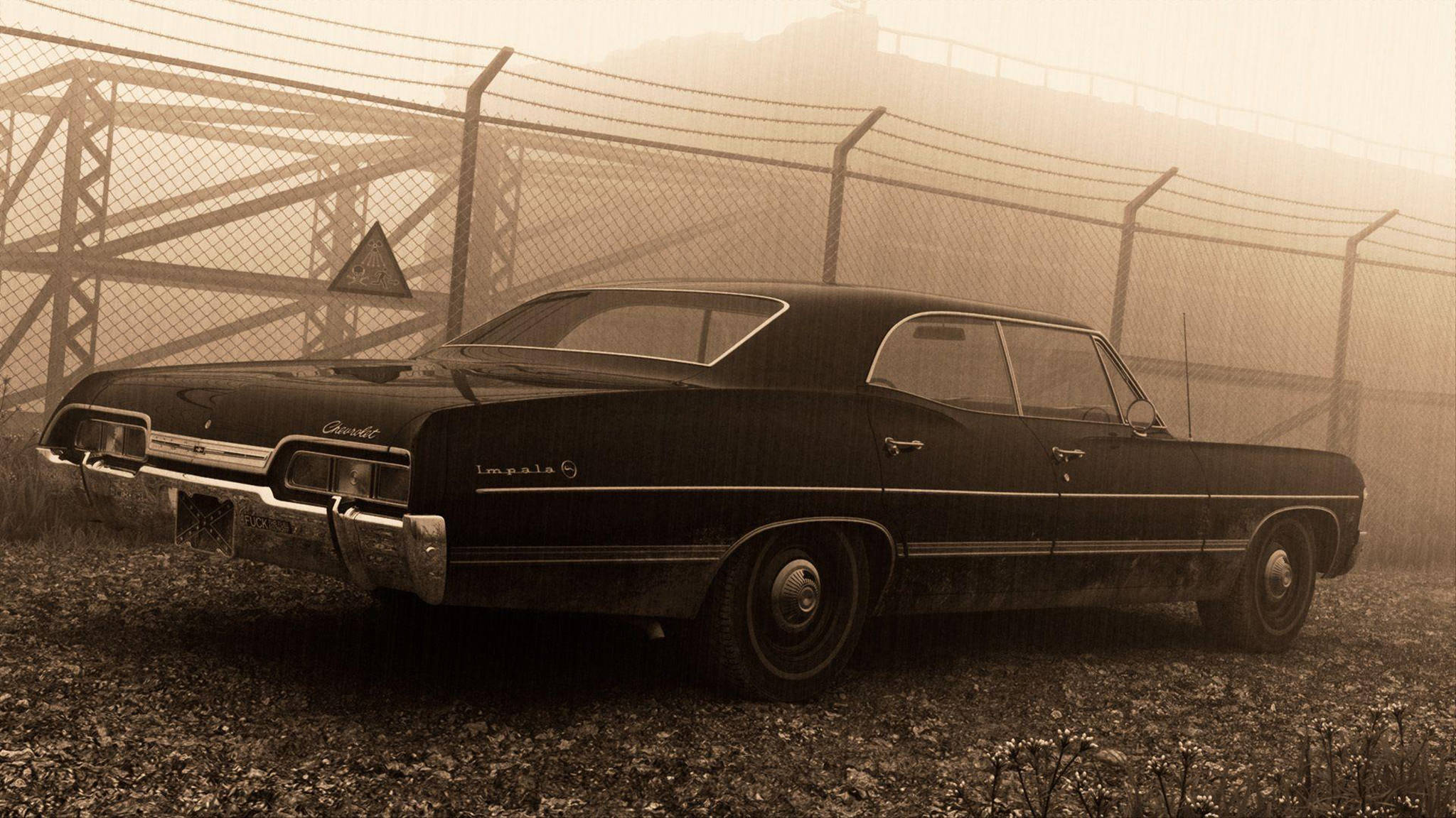 經典1967款雪佛蘭Impala 壁紙 — 一架復古黑色雪佛蘭Impala被遺棄在碎石上，後面有鐵絲網圍欄，場景朦朧，呈現懷舊的棕褐色調。