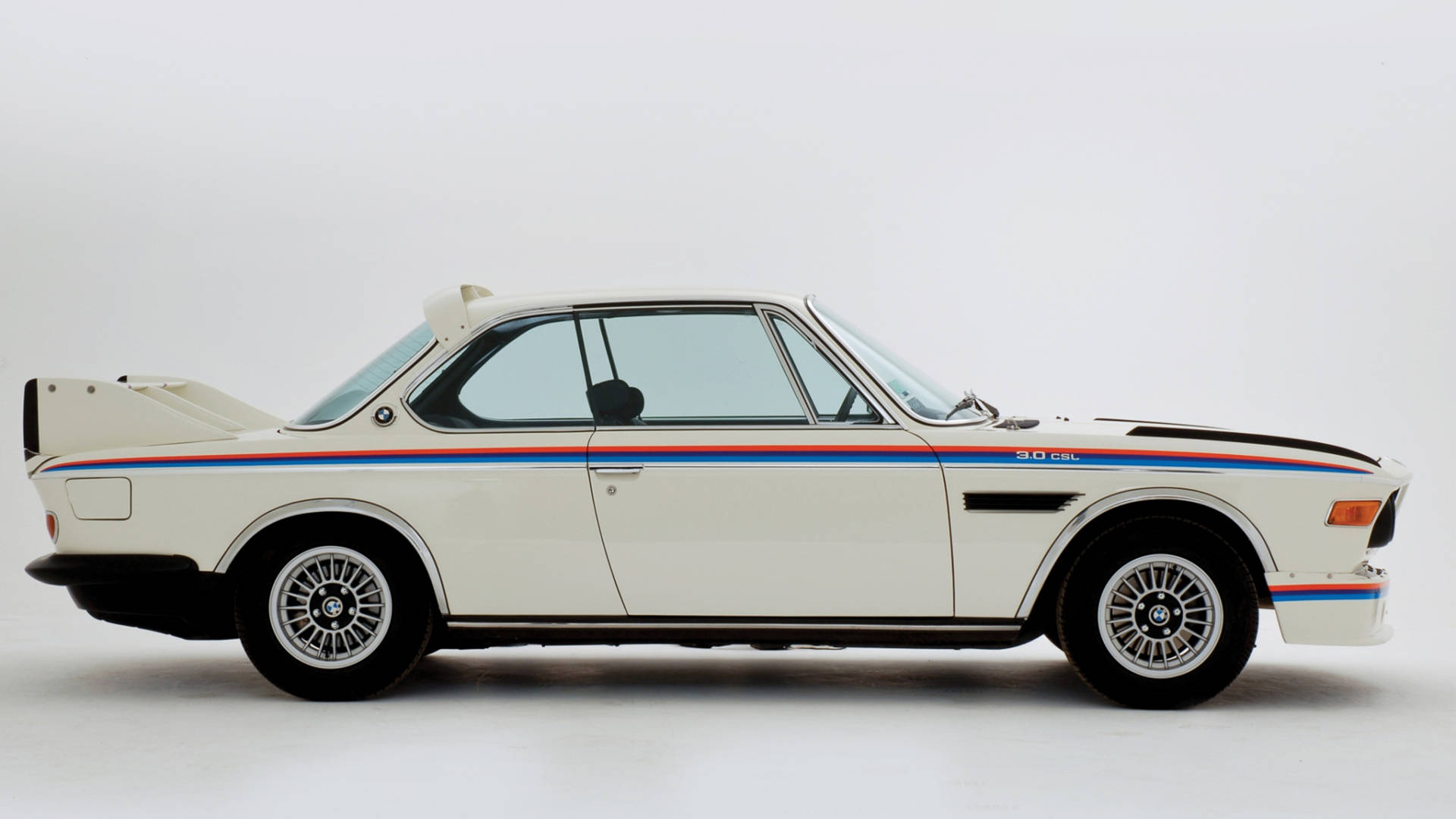帶有藍色、紅色和黑色條紋的白色BMW 3.0 CSL賽車在攝影棚