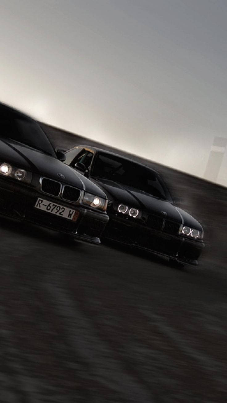 兩輛黑色BMW在黃昏的賽道上疾馳