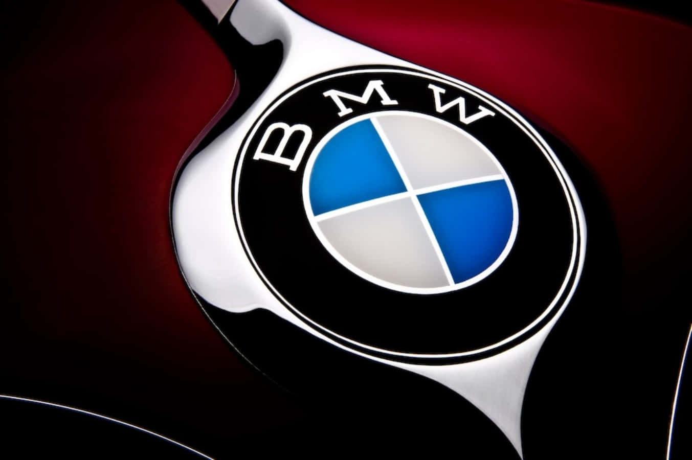 經典BMW標誌特寫 壁紙 — 特寫：在戲劇性燈光下，深紅色引擎蓋上閃亮的BMW標誌。