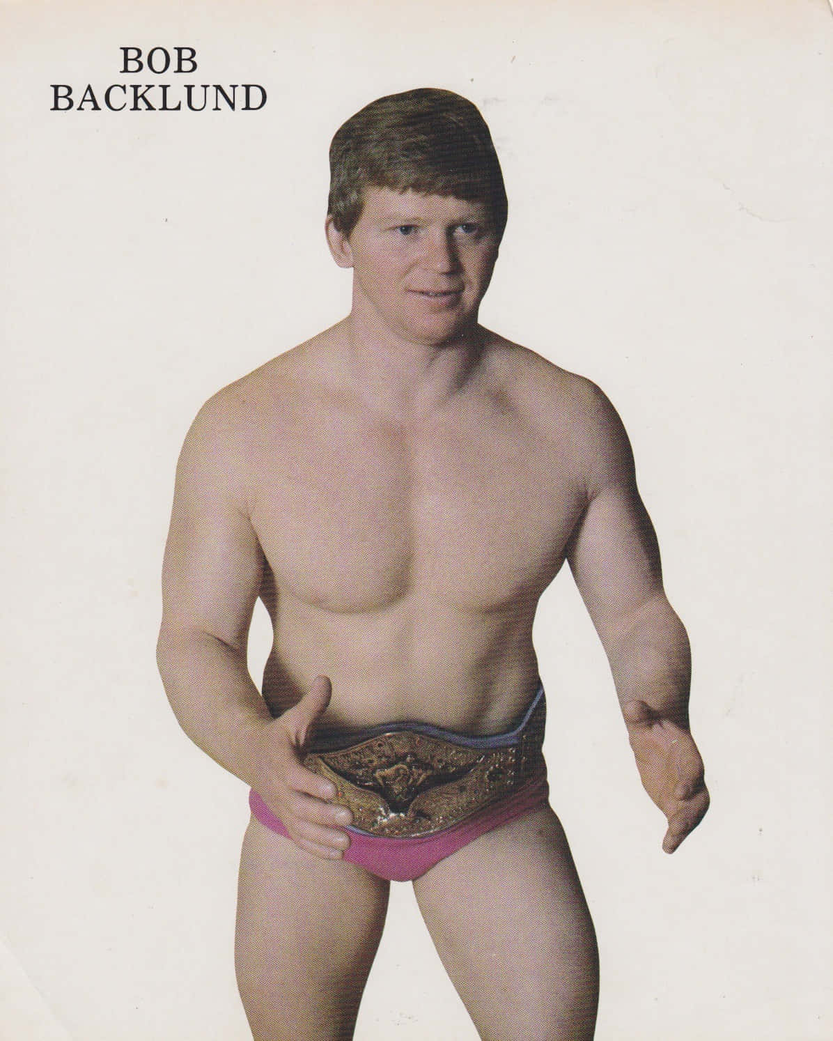 摔角手 Bob Backlund 穿著粉紅色短褲，手持冠軍腰帶。