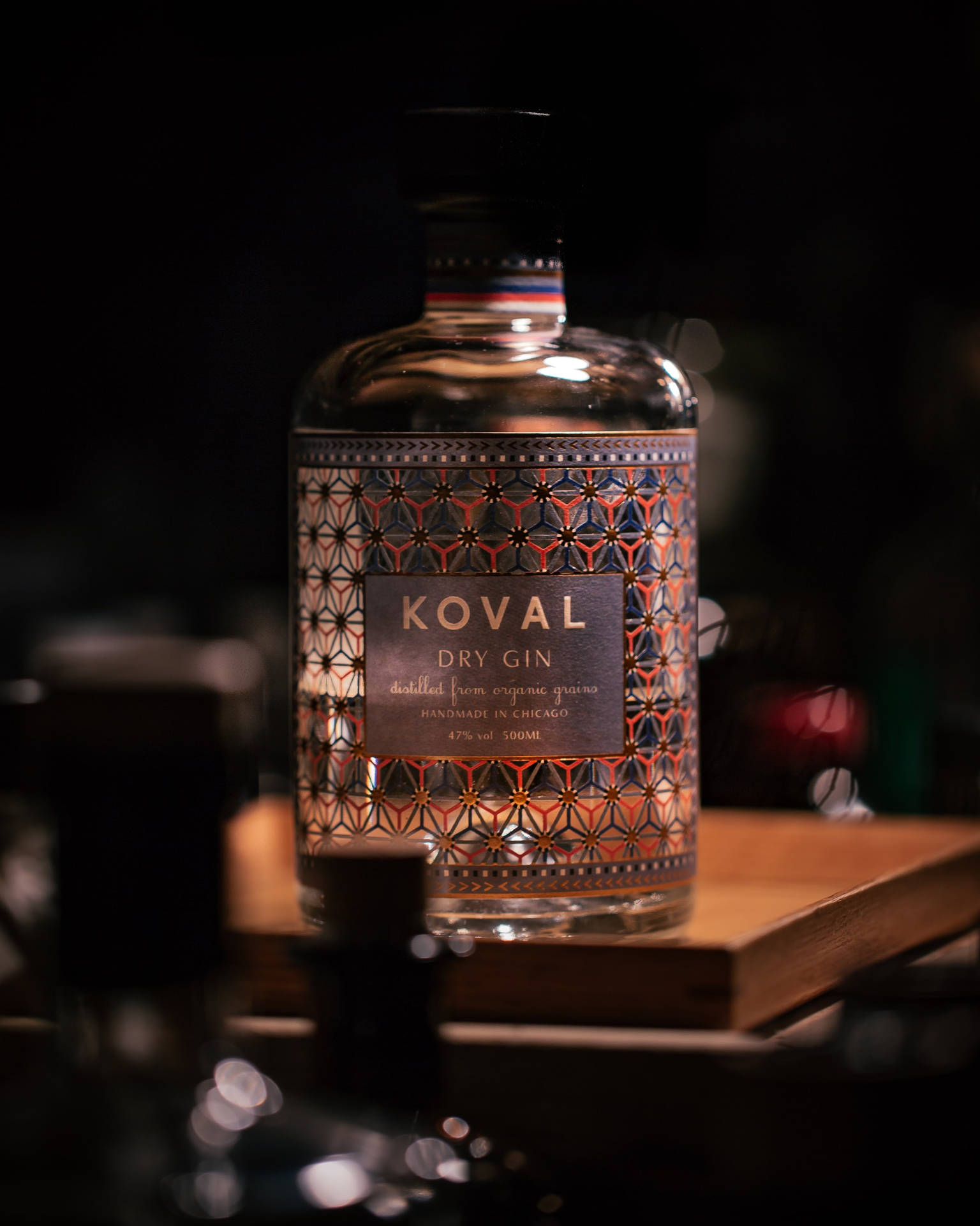 一瓶Koval乾琴酒放在昏暗光線下的木質表面上。