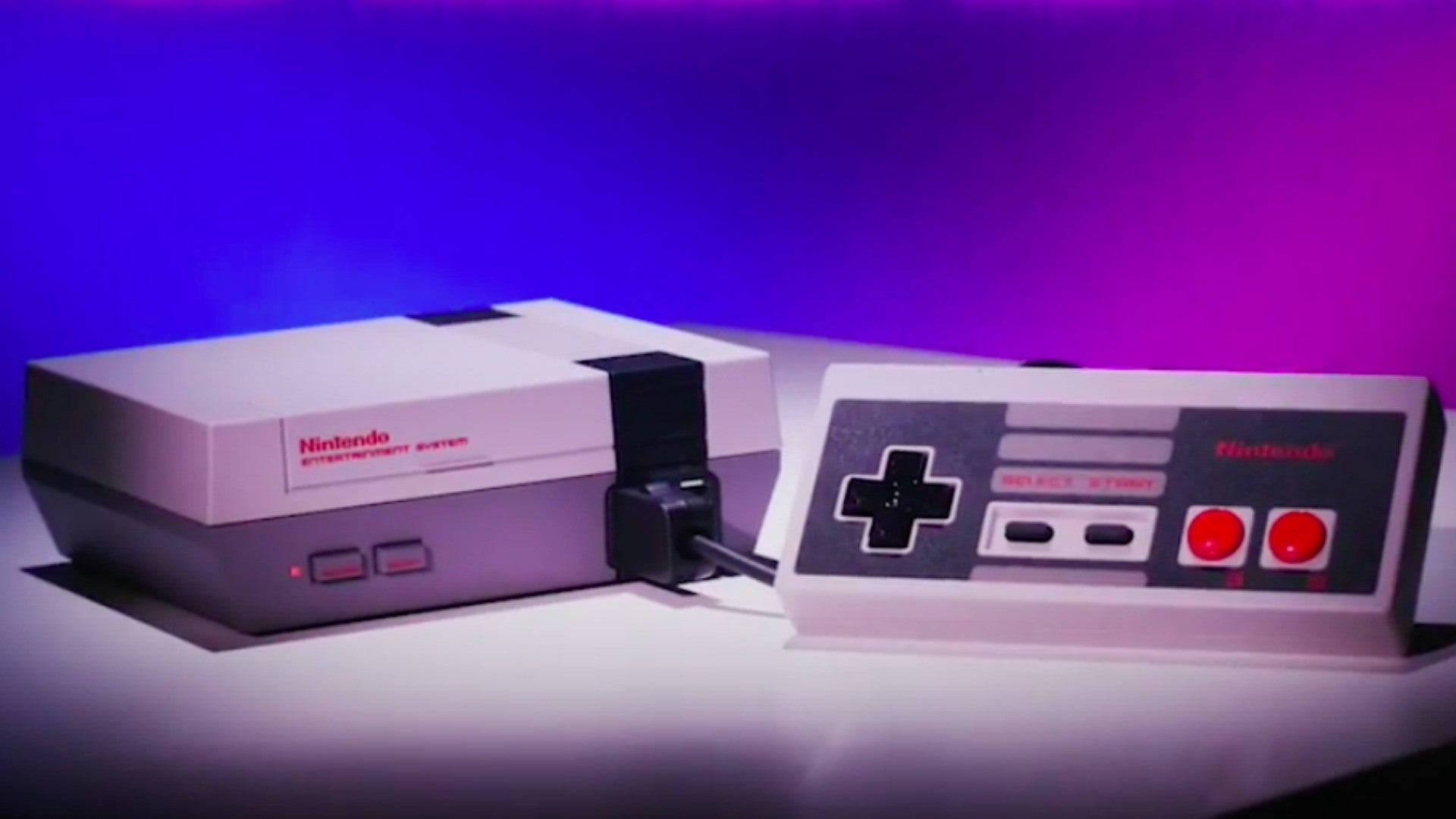經典NES遊戲套裝 壁紙 — 一部復古的Nintendo Entertainment System主機和控制器在充滿活力的紫色和藍色工作室燈光下發光。