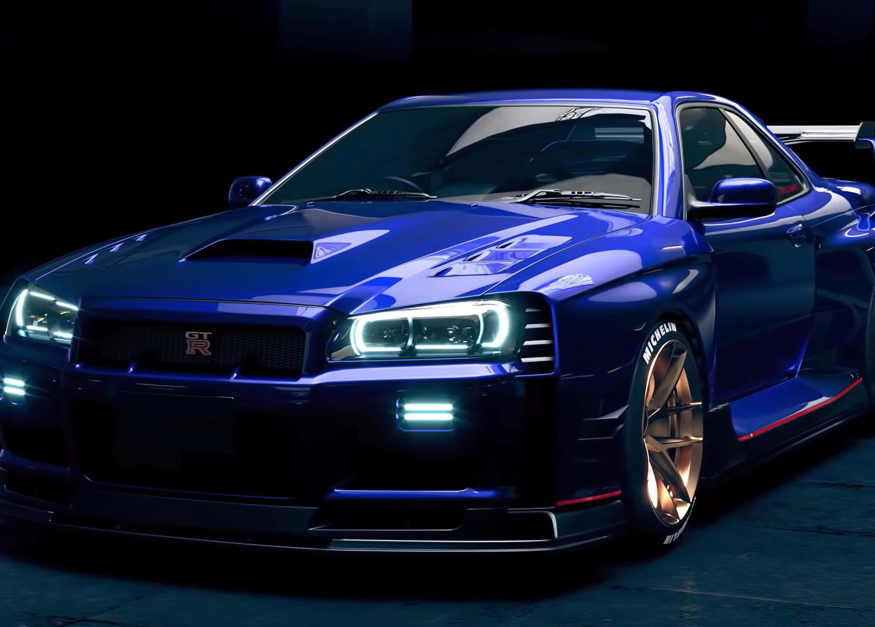 經典Nismo R33 GT-R街頭風采 壁紙 — 一輛光澤藍色日產GT-R跑車，配備發光頭燈和金色輪圈，在黑暗的攝影棚中展示。