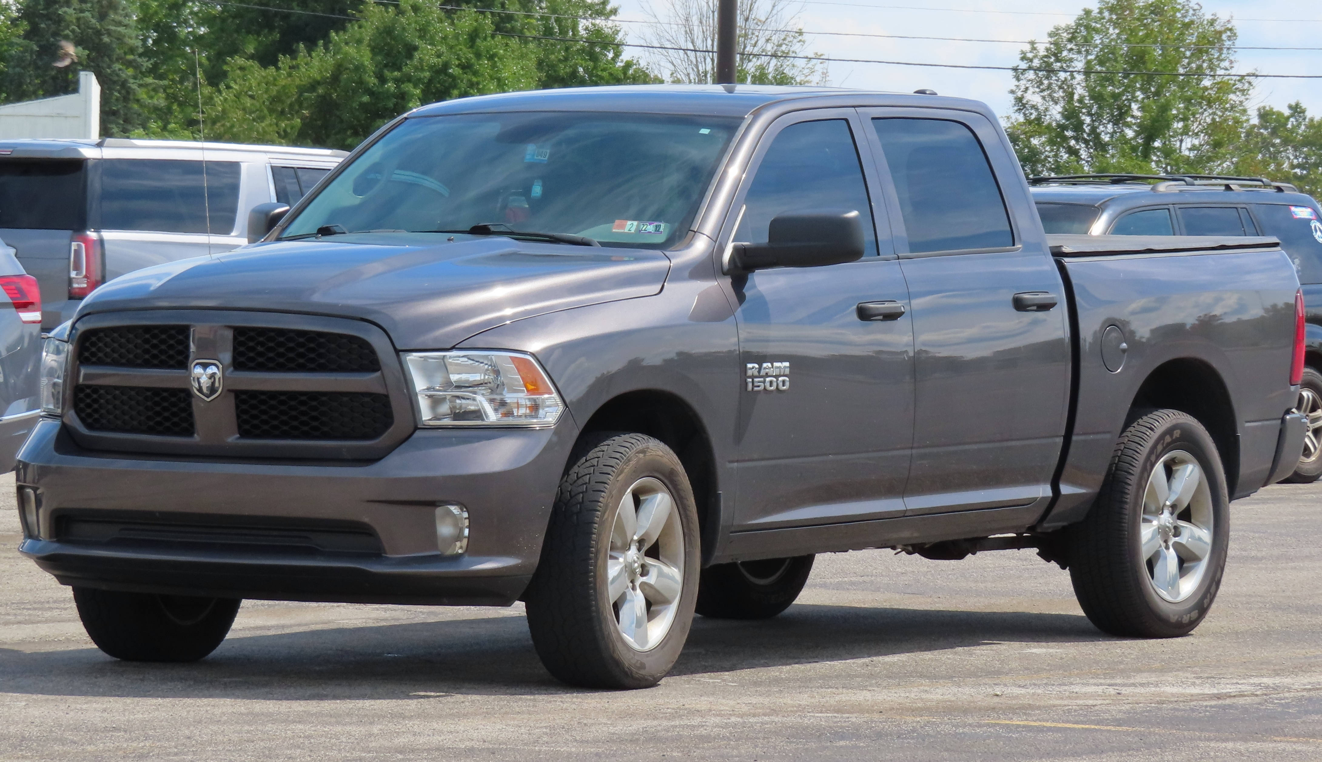 經典RAM 1500卡車 壁紙 — 一架時尚的灰色道奇 Ram 1500 皮卡車停泊在停車場，背景有樹木和其他車輛。
