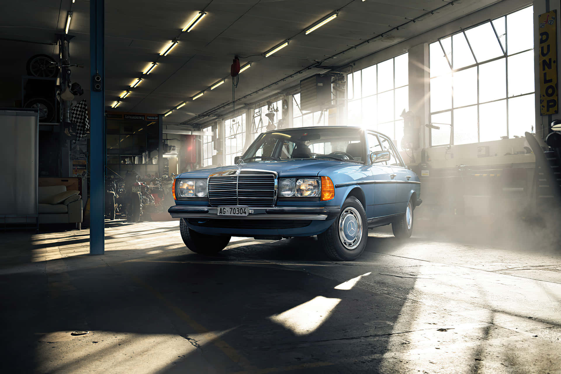 經典藍色 Mercedes-Benz 房車在佈滿灰塵的車庫中沐浴陽光。
