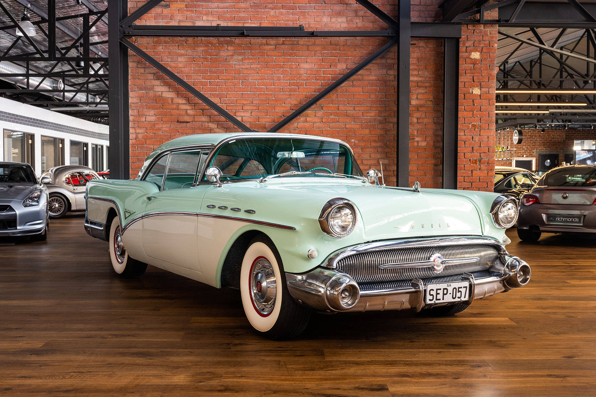 復古薄荷綠色1957年Buick Roadmaster，帶有鍍鉻細節，陳列在磚牆的汽車展廳中。