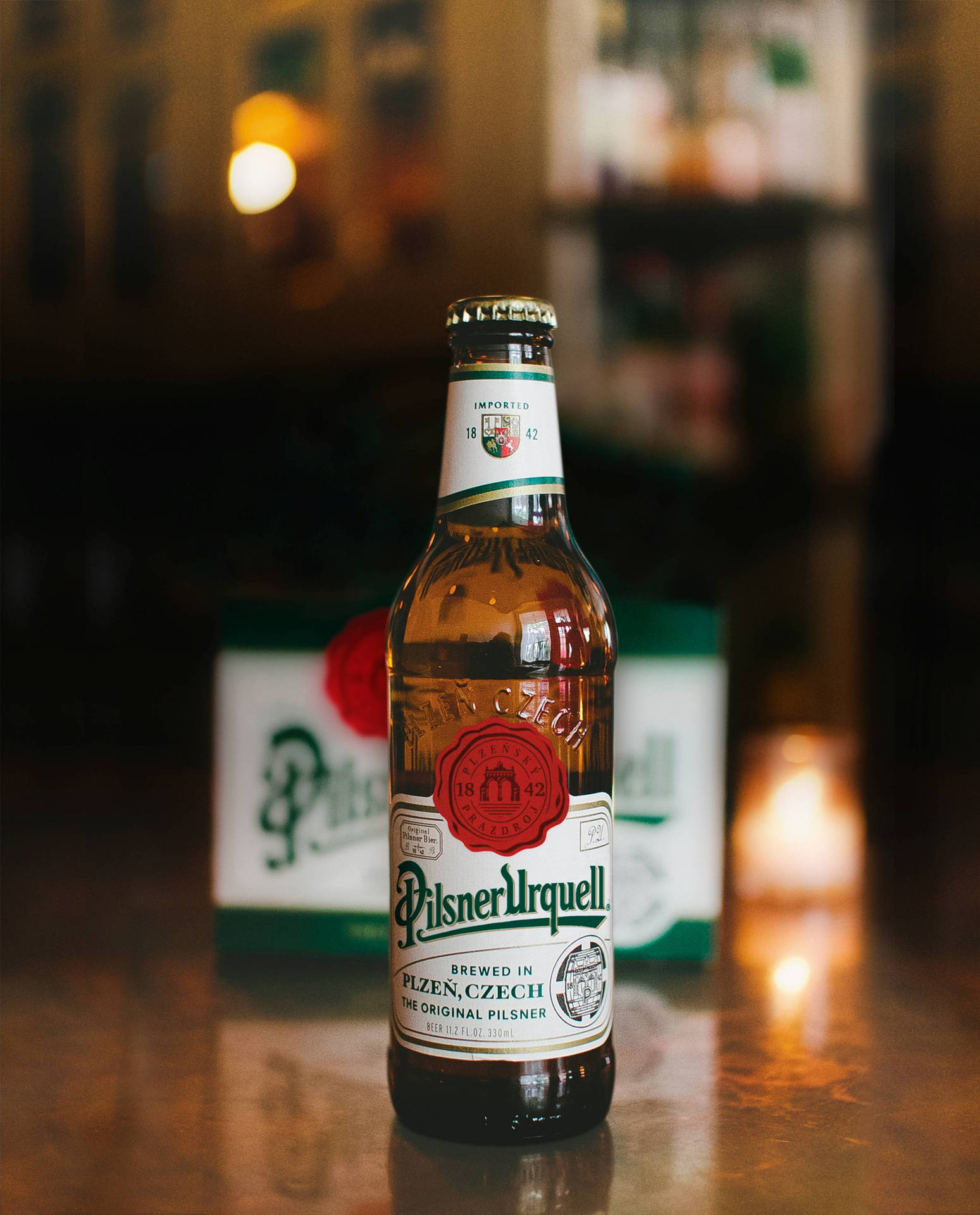 一瓶Pilsner Urquell啤酒在木製吧檯上，燭光氛圍。