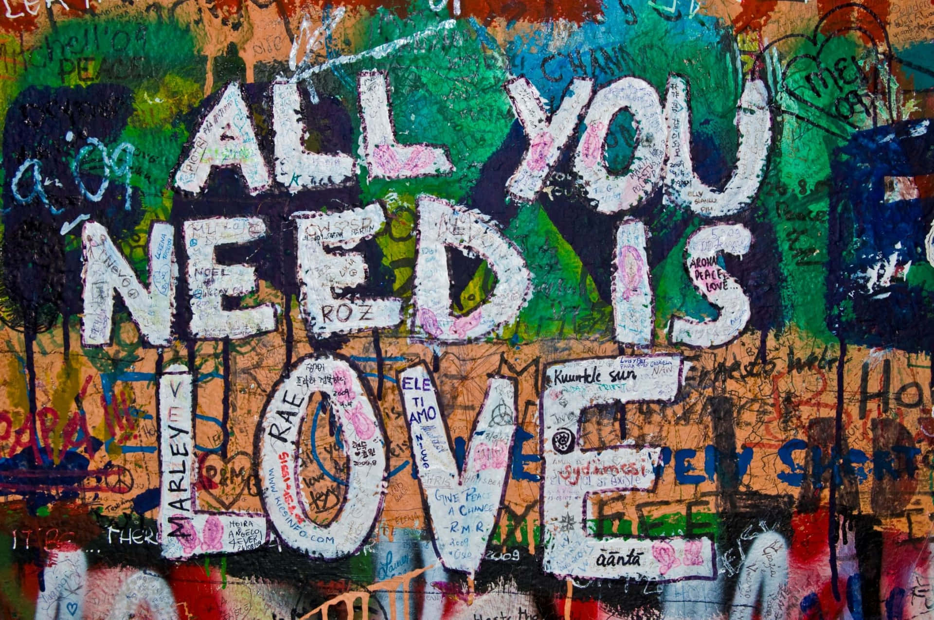 塗鴉牆，在彩色標籤上用白色油漆寫著「All You Need Is Love」。