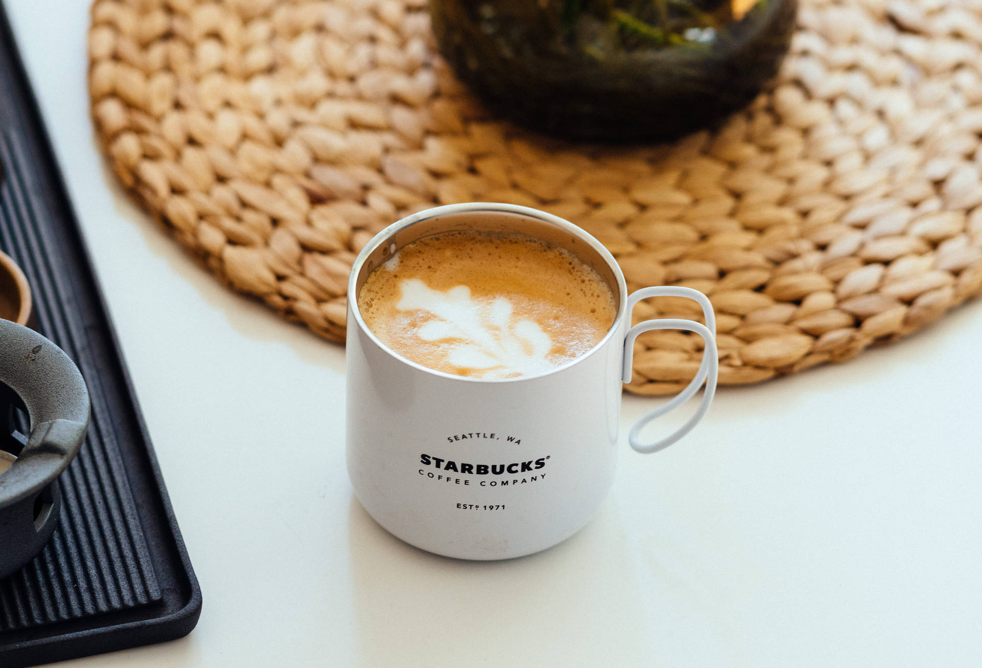 白色Starbucks咖啡馬克杯，編織墊上帶葉子設計。 — 星巴克 壁紙