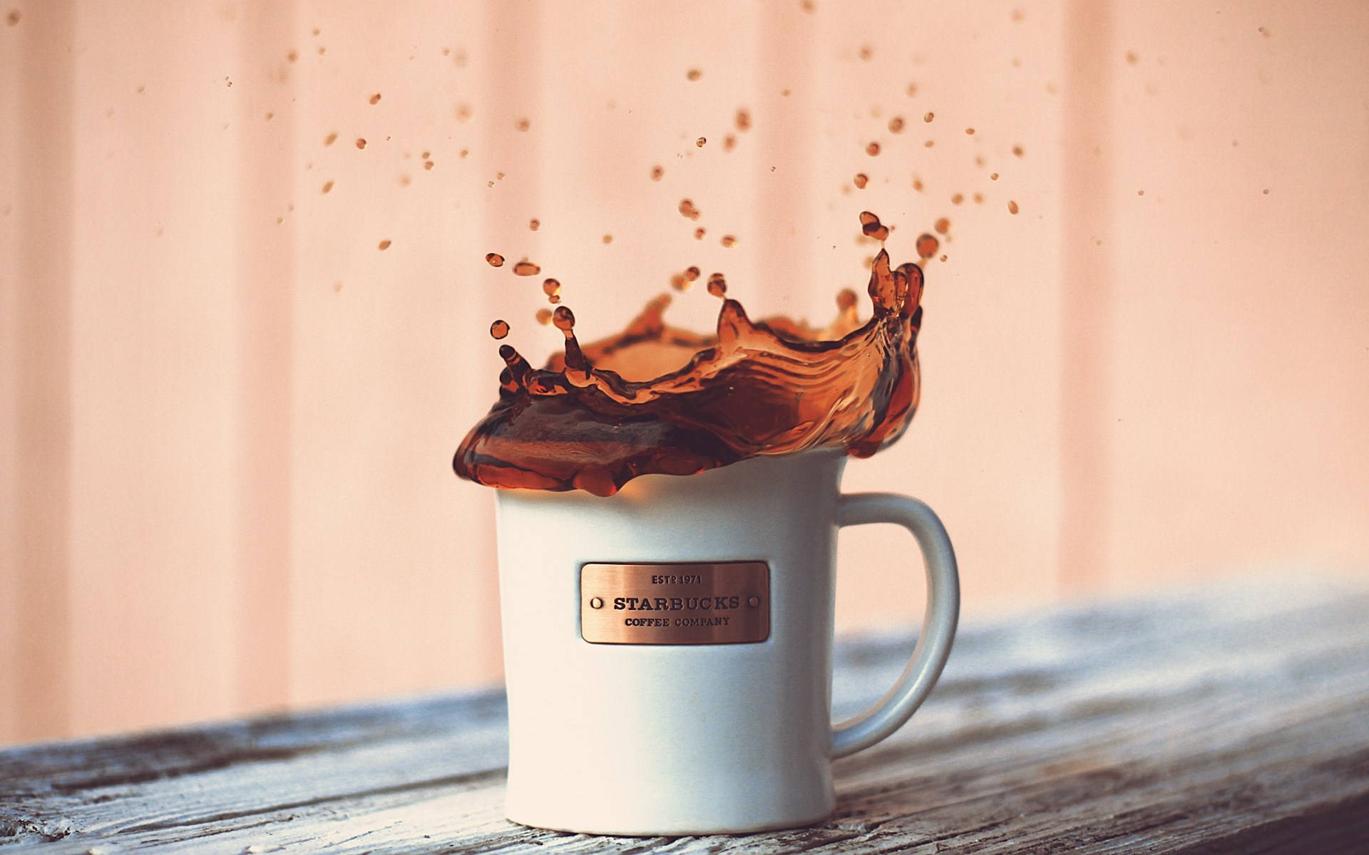 咖啡從木質表面上的 Starbucks 杯子中濺出。