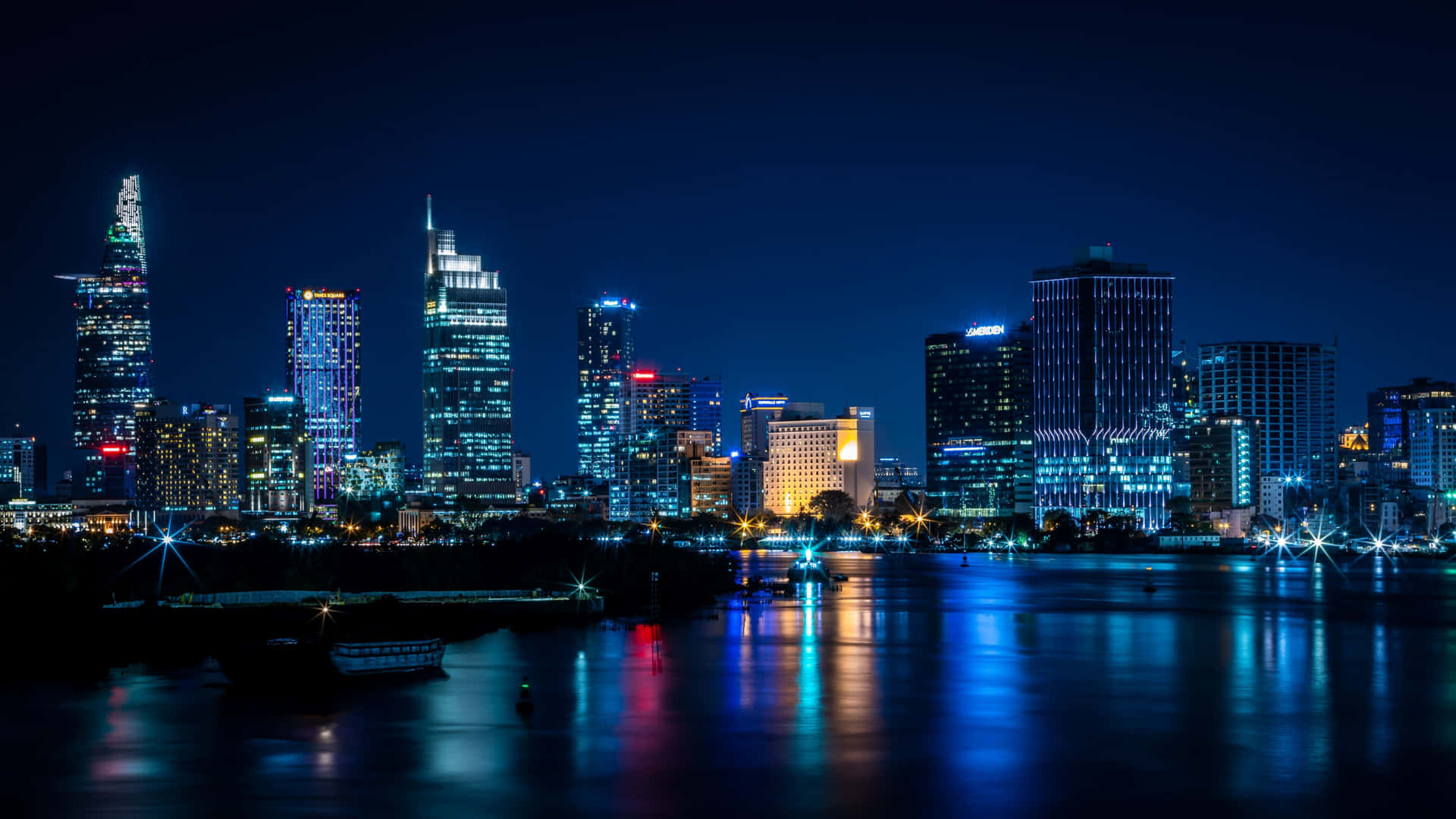 夜晚城市景觀，發光的摩天大樓倒映在河流中。