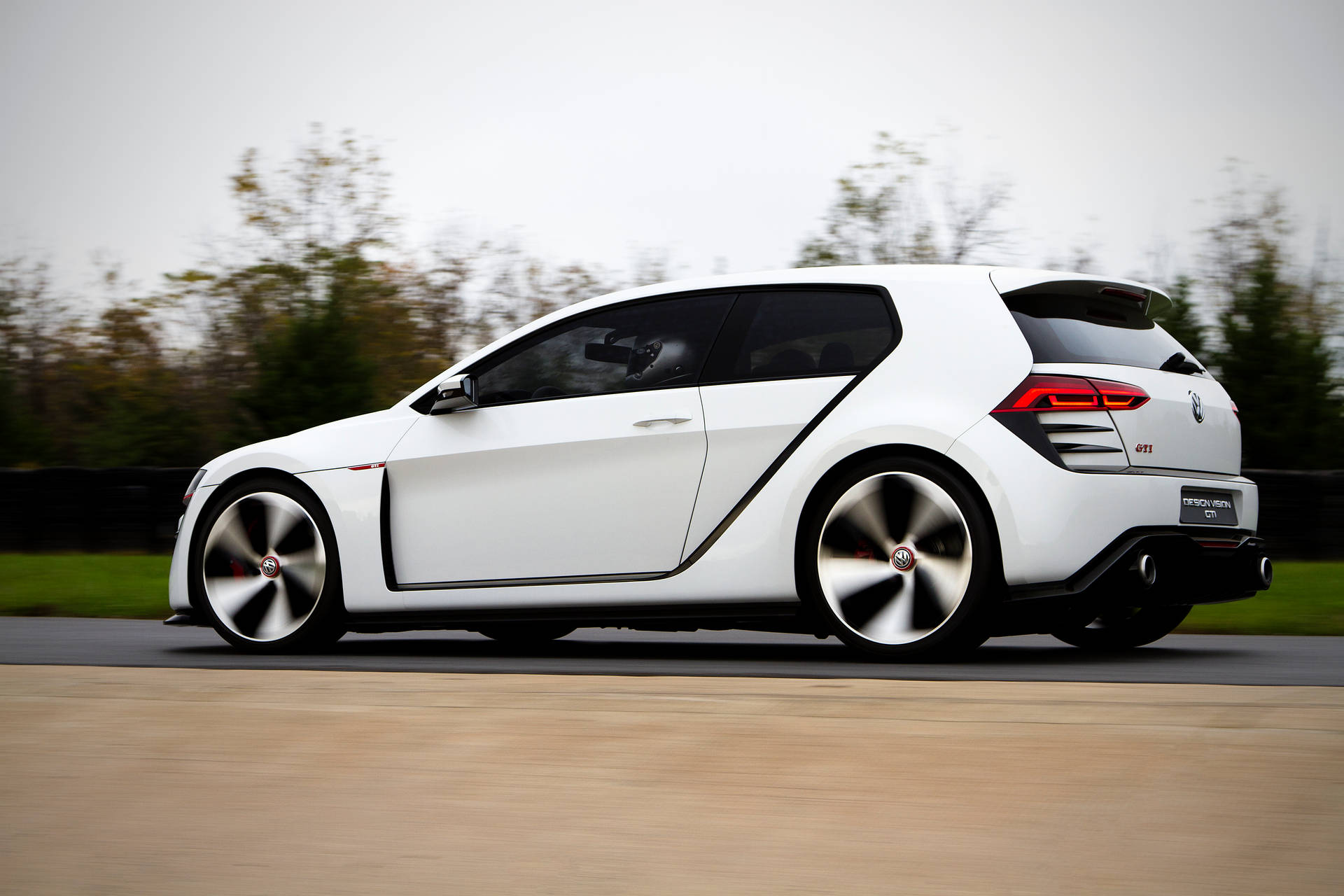 白色Volkswagen Golf GTI Concept在秋樹間的道路上飛馳。