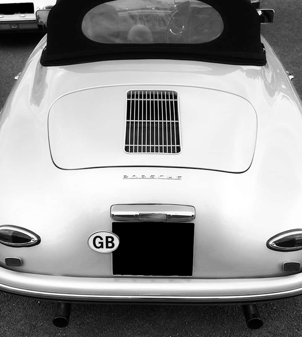 Car Hood 桌布 壁紙 — 經典白色保時捷356開篷車的後視圖，配黑色軟頂和GB貼紙，黑白風格。
