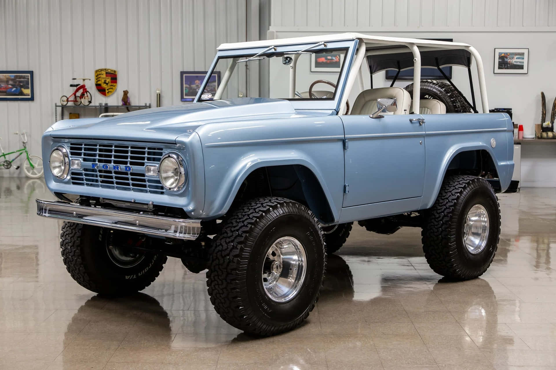 車庫中淺藍色經典福特Bronco，帶有鍍鉻細節和大輪胎。