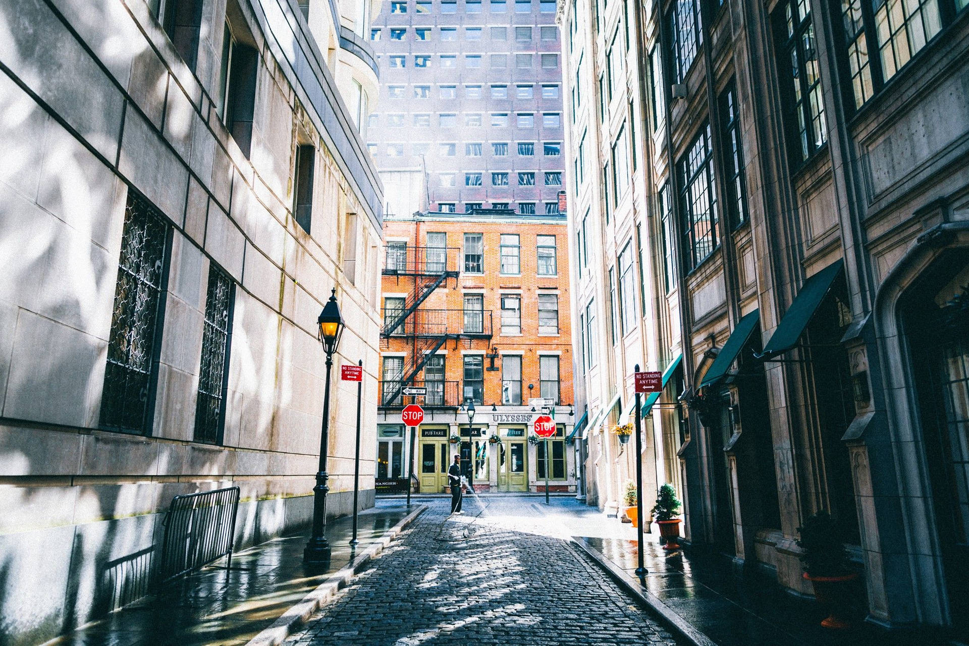 歷史建築與現代建築之間的狹窄鵝卵石小巷，有陽光和雨水。