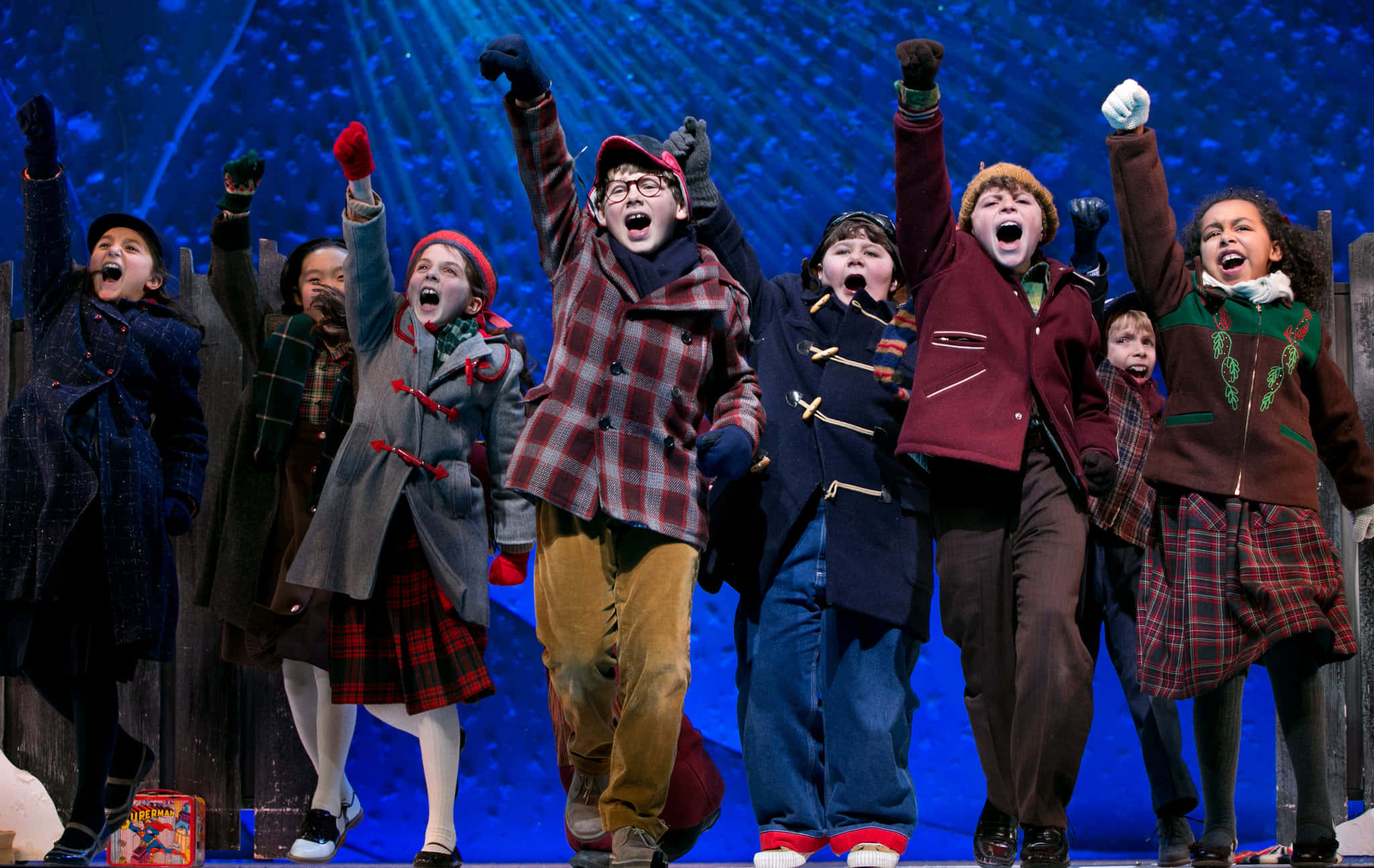 經典聖誕電影《A Christmas Story》 壁紙 — 穿著冬季外套的孩子們在藍色星空背景的舞台上高興地舉起手臂並呼喊。