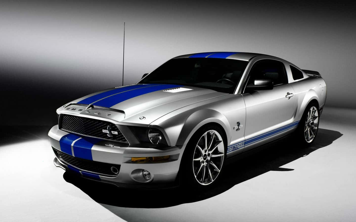 銀色 Shelby GT500 跑車，帶有藍色賽車條紋，在工作室燈光下。