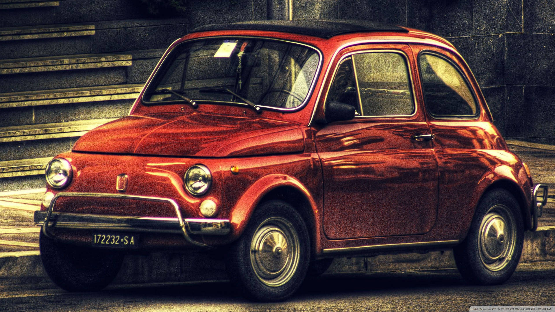 復古紅色Fiat 500停泊在石階附近的城市街道上。