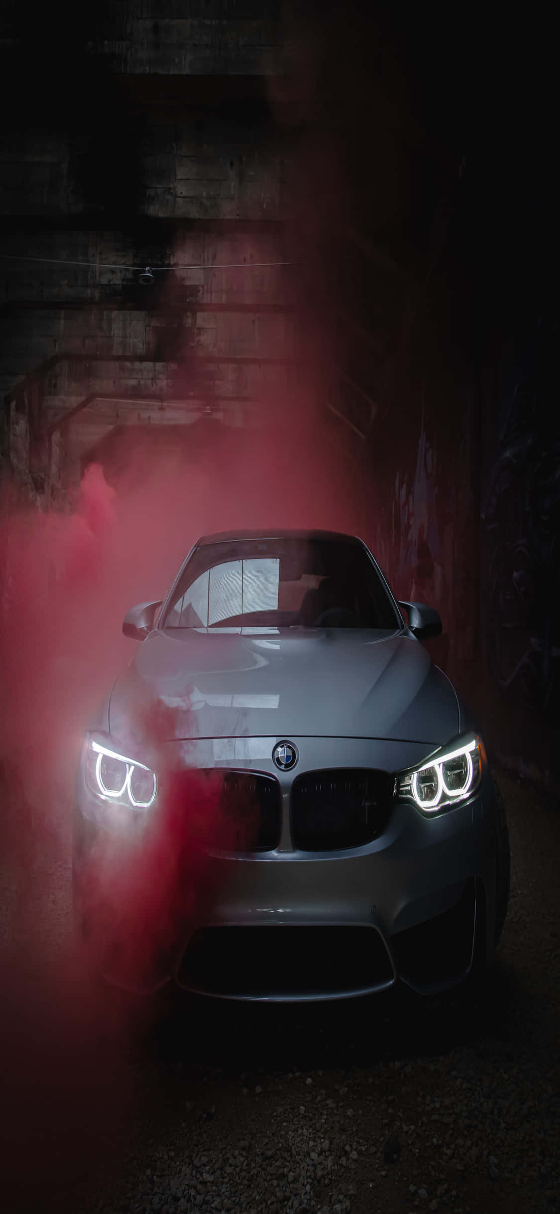 經典豪華遇上高科技時尚 壁紙 — 一輛銀色BMW跑車在黑暗的混凝土隧道中從紅煙中出現，車頭燈發光。