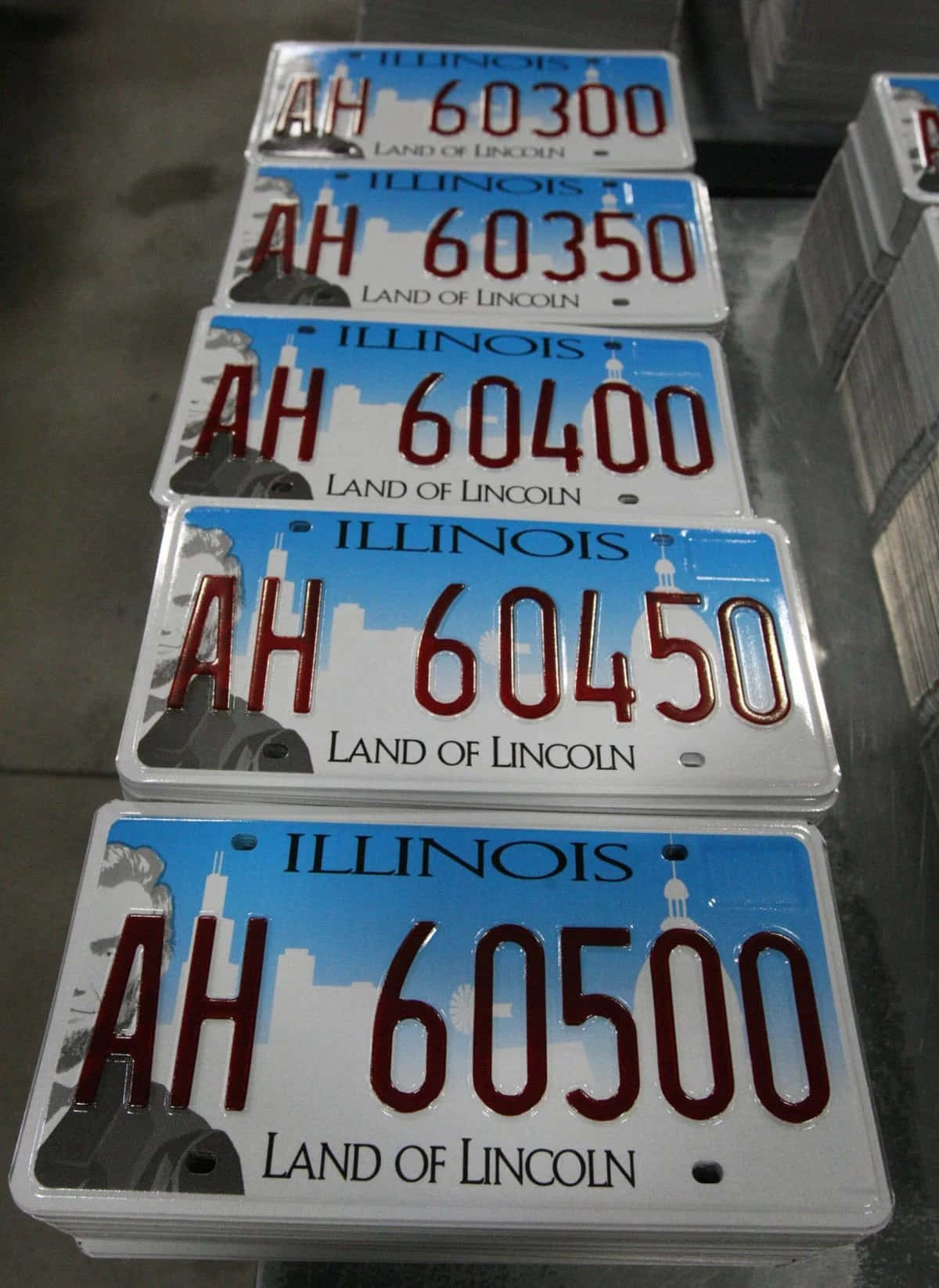 經典車牌 壁紙 — 堆疊的伊利諾伊州車牌，序列號 AH 60300 至 60500，展示「Land of Lincoln」標語和城市天際線設計。