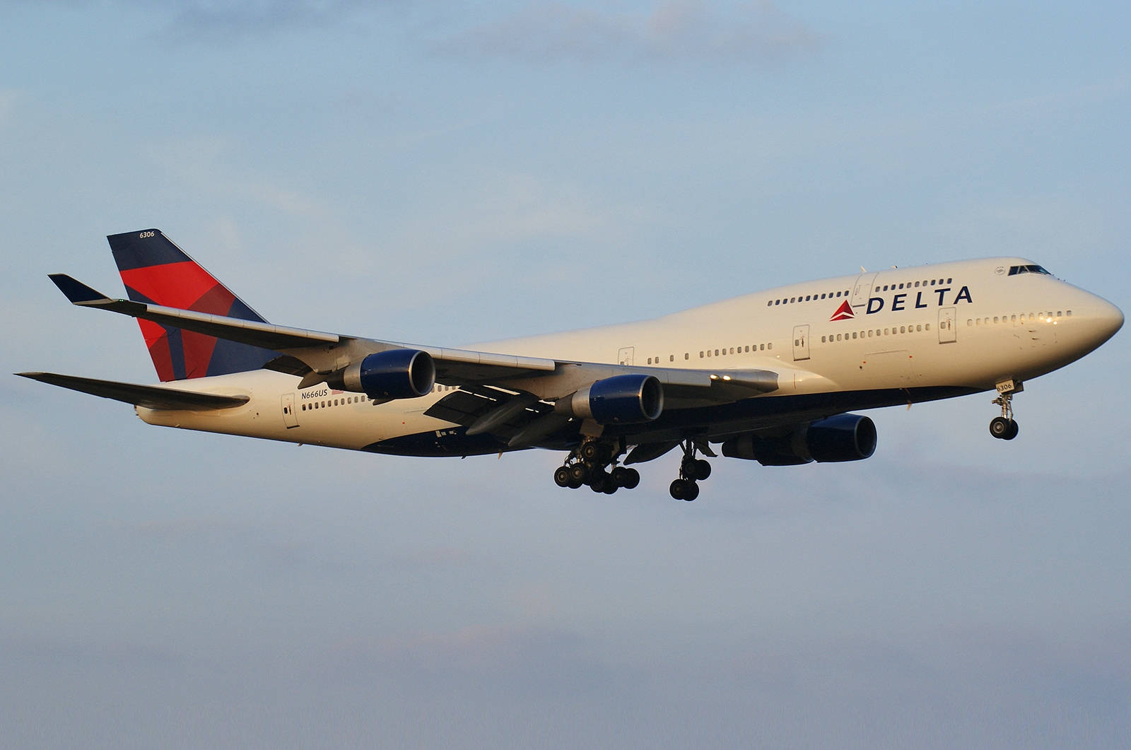 達美波音747飛機降落，起落架放下，藍天背景。