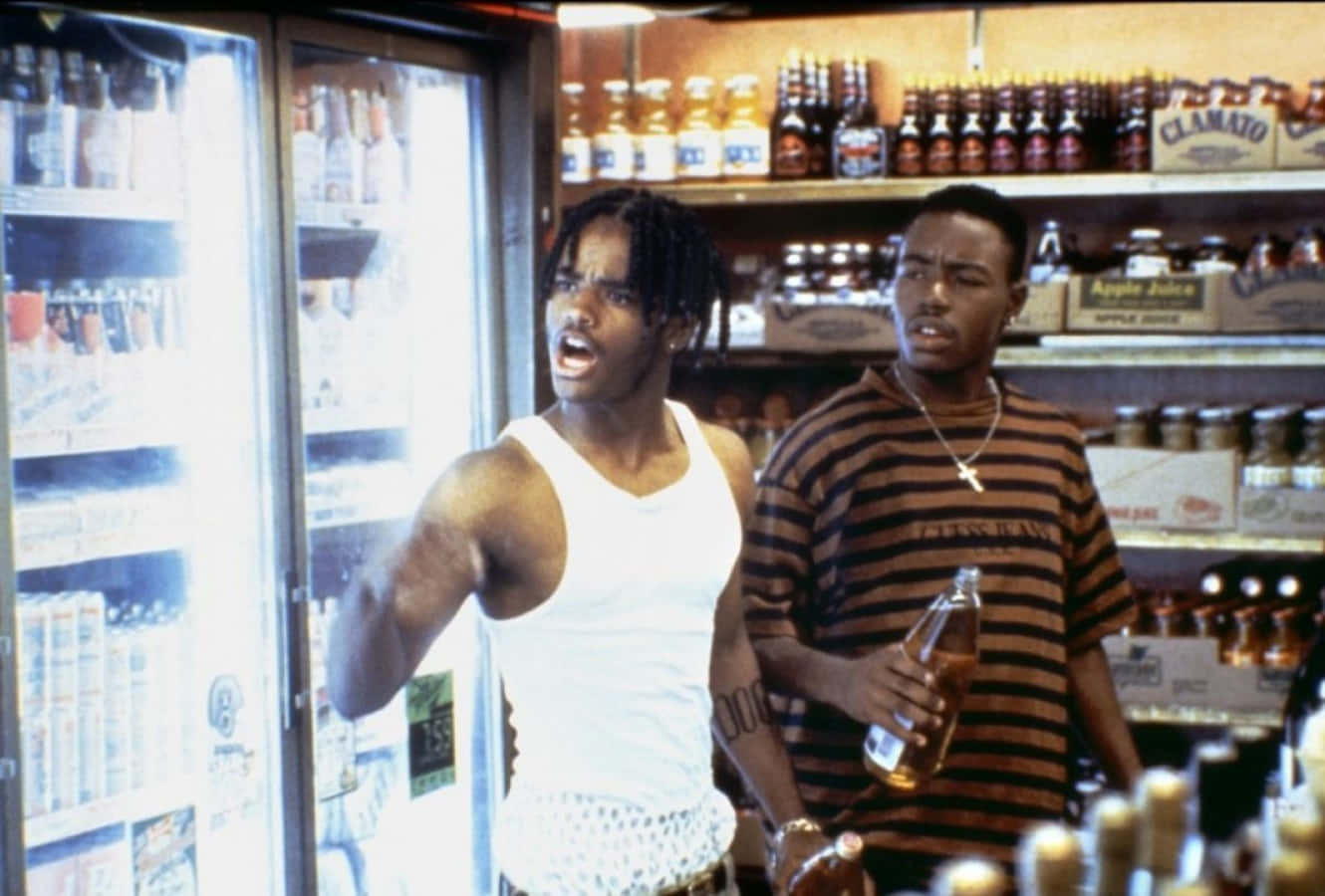 經典鉅作《Menace II Society》電影影像 壁紙 — 便利店內有兩名男子，一人憤怒地大喊，手持一個瓶子，另一人則手持瓶子旁觀。