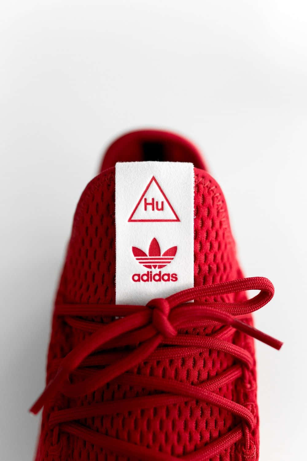 白色背景上帶有Hu品牌標識和鞋帶的紅色Adidas運動鞋。