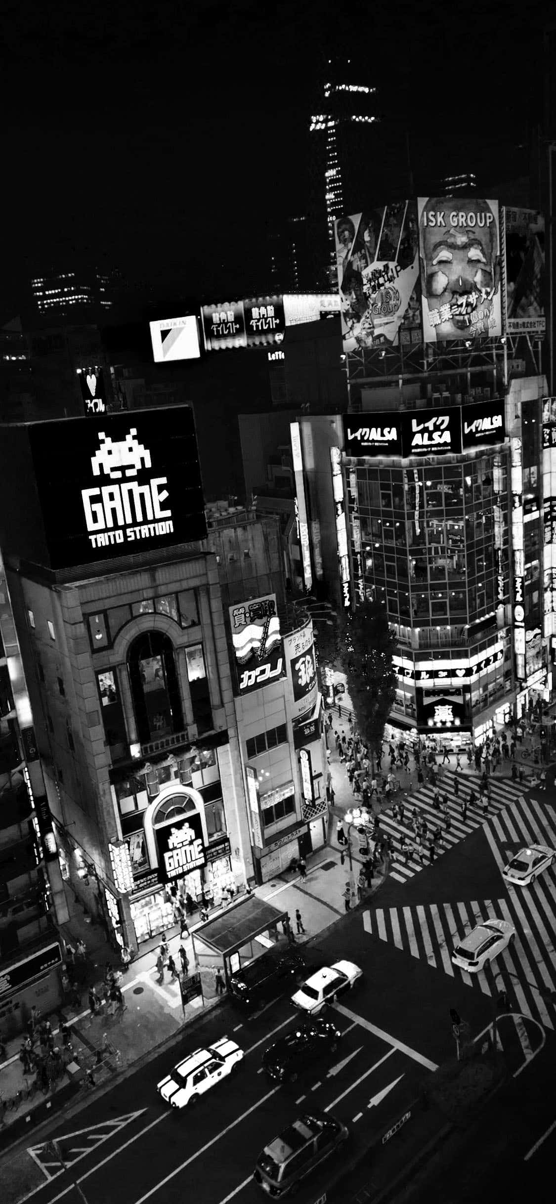 經典風格與現代科技的完美結合 — 黑白 iPhone 壁紙 — 一張高角度黑白照片，拍攝了夜晚繁忙的東京街道，有發光的廣告牌和過馬路的行人。