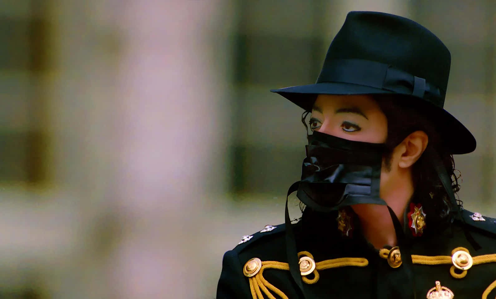 米高積遜身穿黑色軍裝制服，帶有金色點綴和黑色帽子，臉部部分被遮蓋。