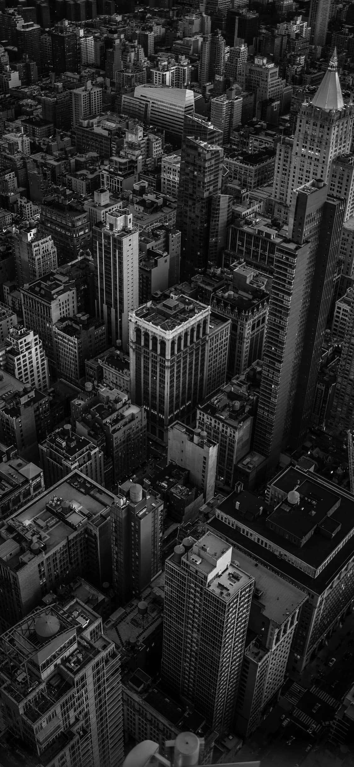 經典黑白 iPhone 圖像 壁紙 — 密集城市天際線的黑白航拍圖，高聳摩天大樓和複雜的屋頂細節。