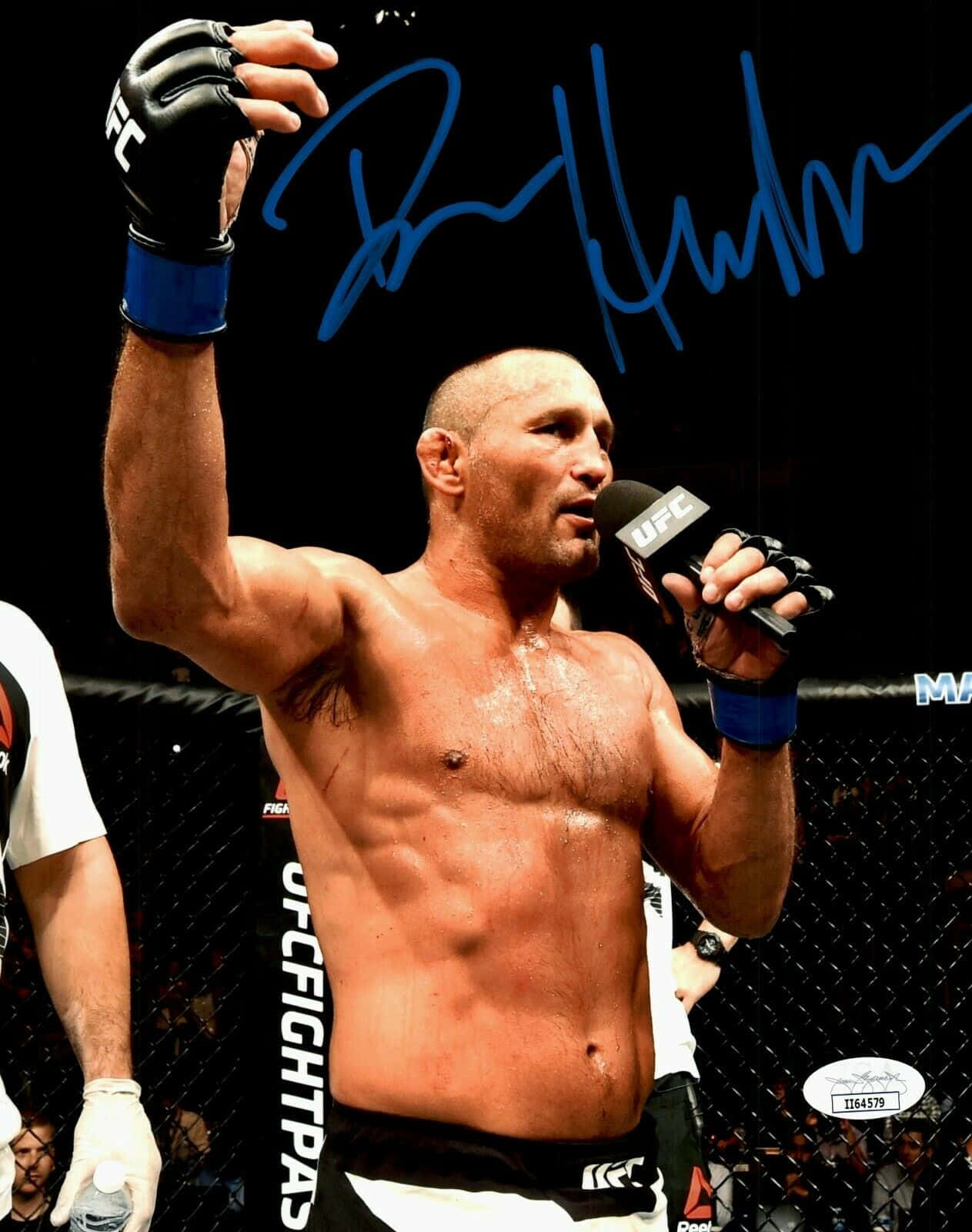 UFC拳手在八角籠內舉拳持咪慶祝勝利。