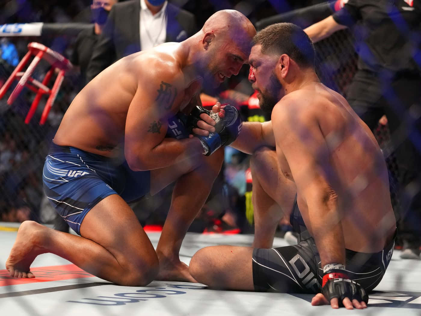 兩名男性MMA拳手在UFC比賽中纏抱，臉上帶血。