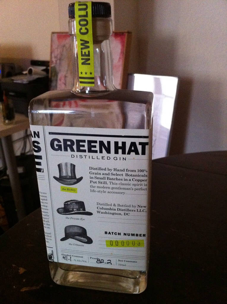一個透明嘅氈酒樽，帶有黃色標籤同標籤上嘅帽子插圖。