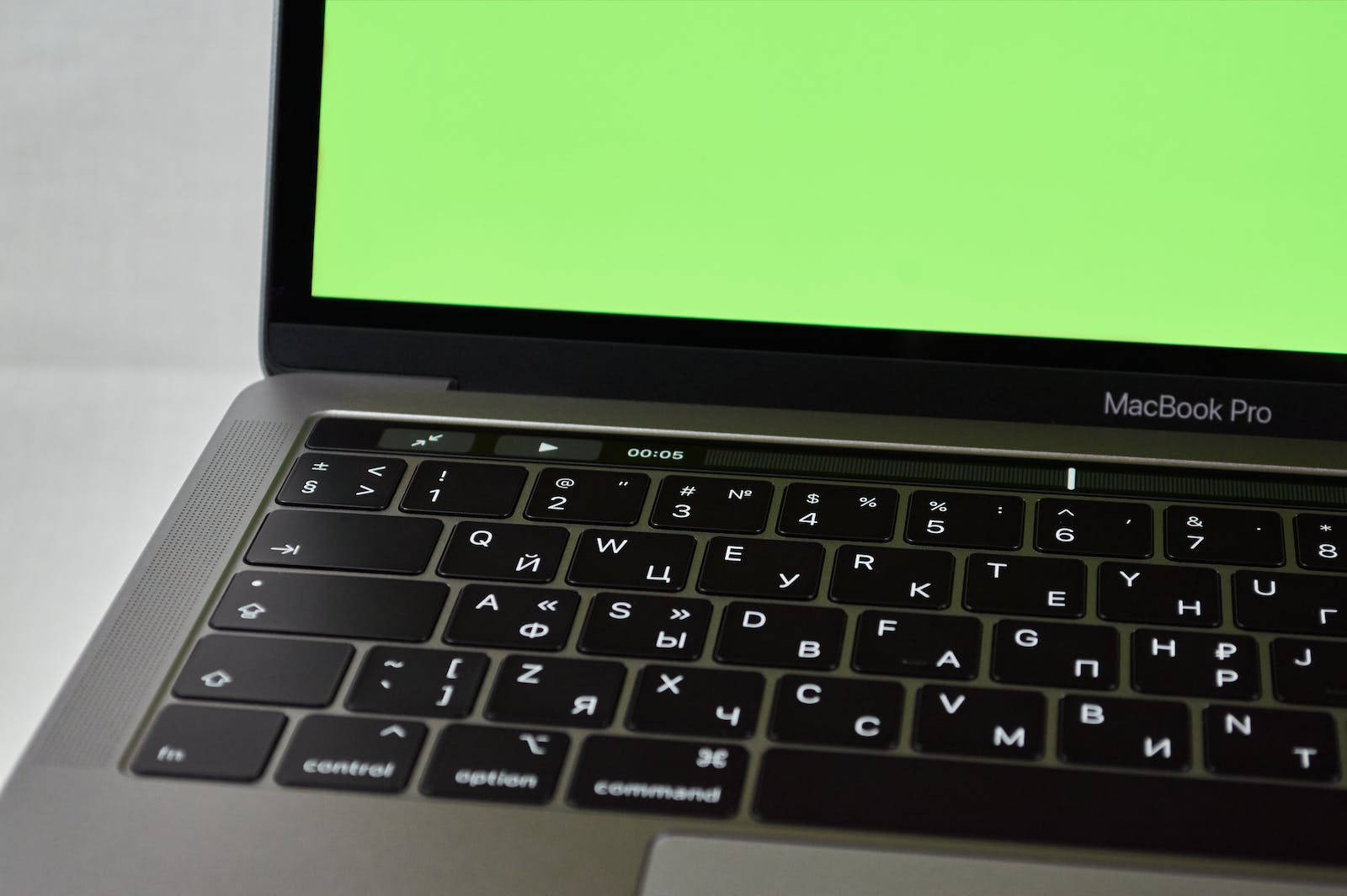 銀色 MacBook Pro，配備西里爾字母鍵盤及顯示計時器的綠色屏幕。