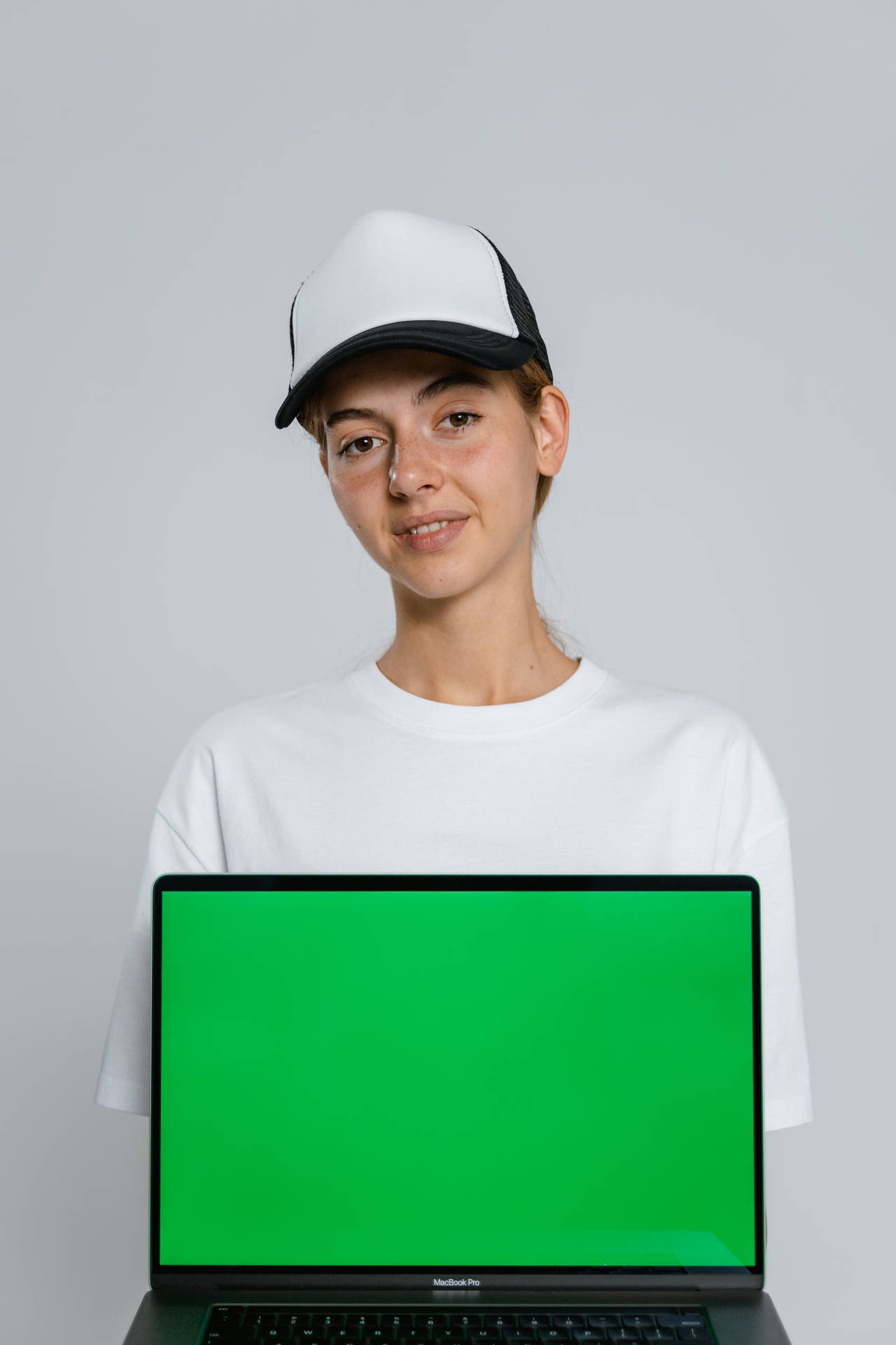 戴帽子的年輕女子拿著帶有綠幕的筆記本電腦 — 美學筆電 壁紙