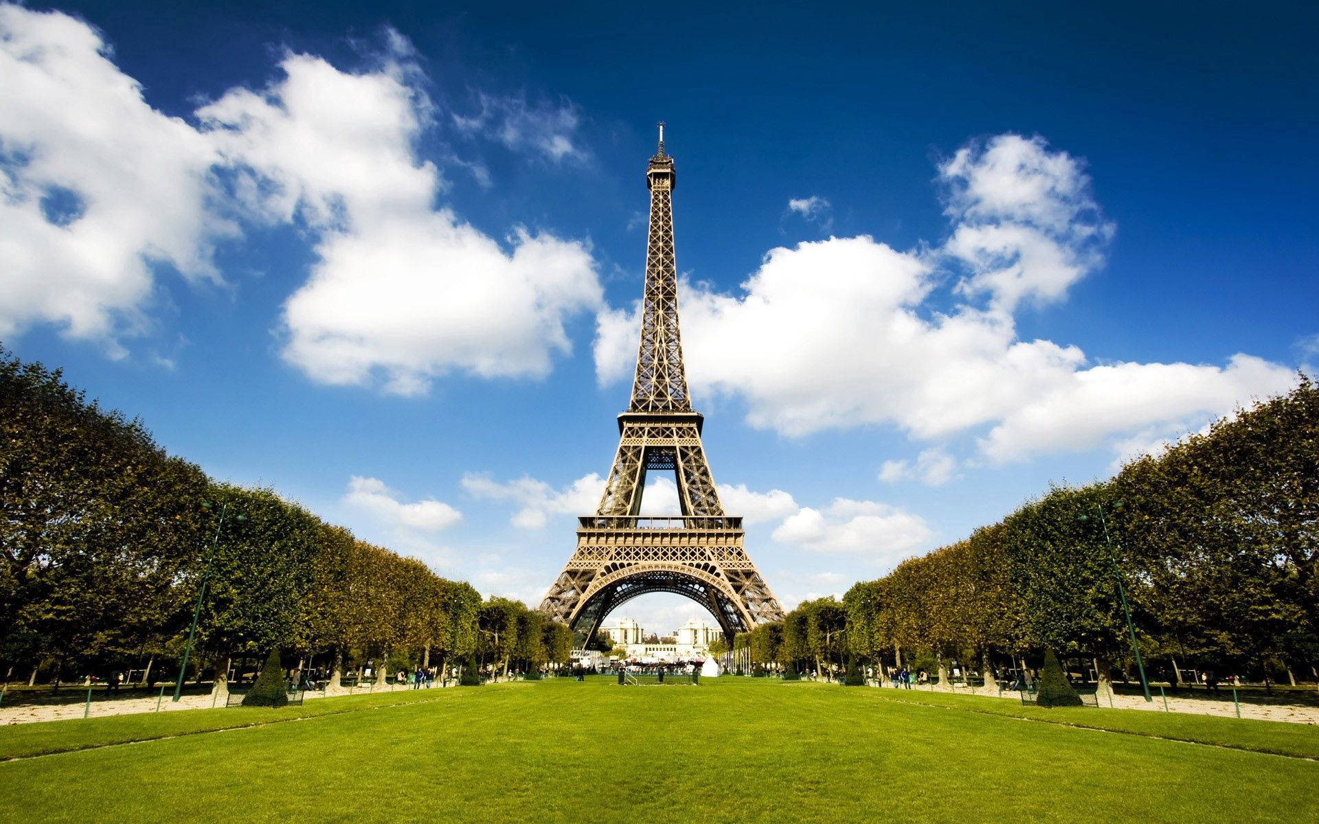 艾菲爾鐵塔在明亮的藍天白雲和前景的綠色公園襯托下