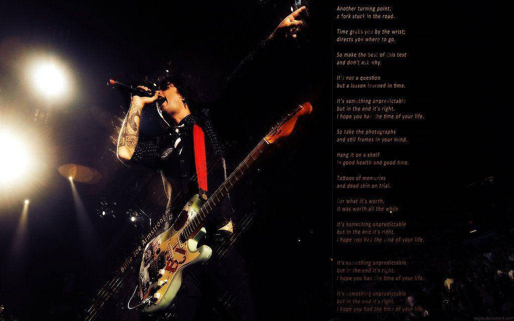 綠日樂隊《Good Riddance》歌詞 壁紙 — 一位有紋身的音樂家熱情地對著咪高峰唱歌，同時在明亮的舞台燈光下彈結他，歌詞覆蓋在黑暗背景上。