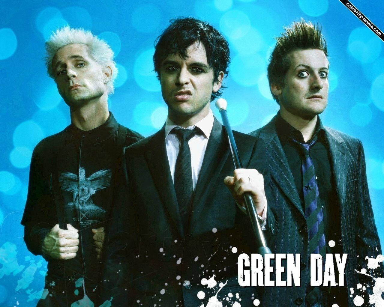 綠日樂隊藍色散景背景 壁紙 — Green Day 的三位樂隊成員在充滿活力的藍色散景背景上，搭配白色油漆飛濺和粗體文字擺姿勢。