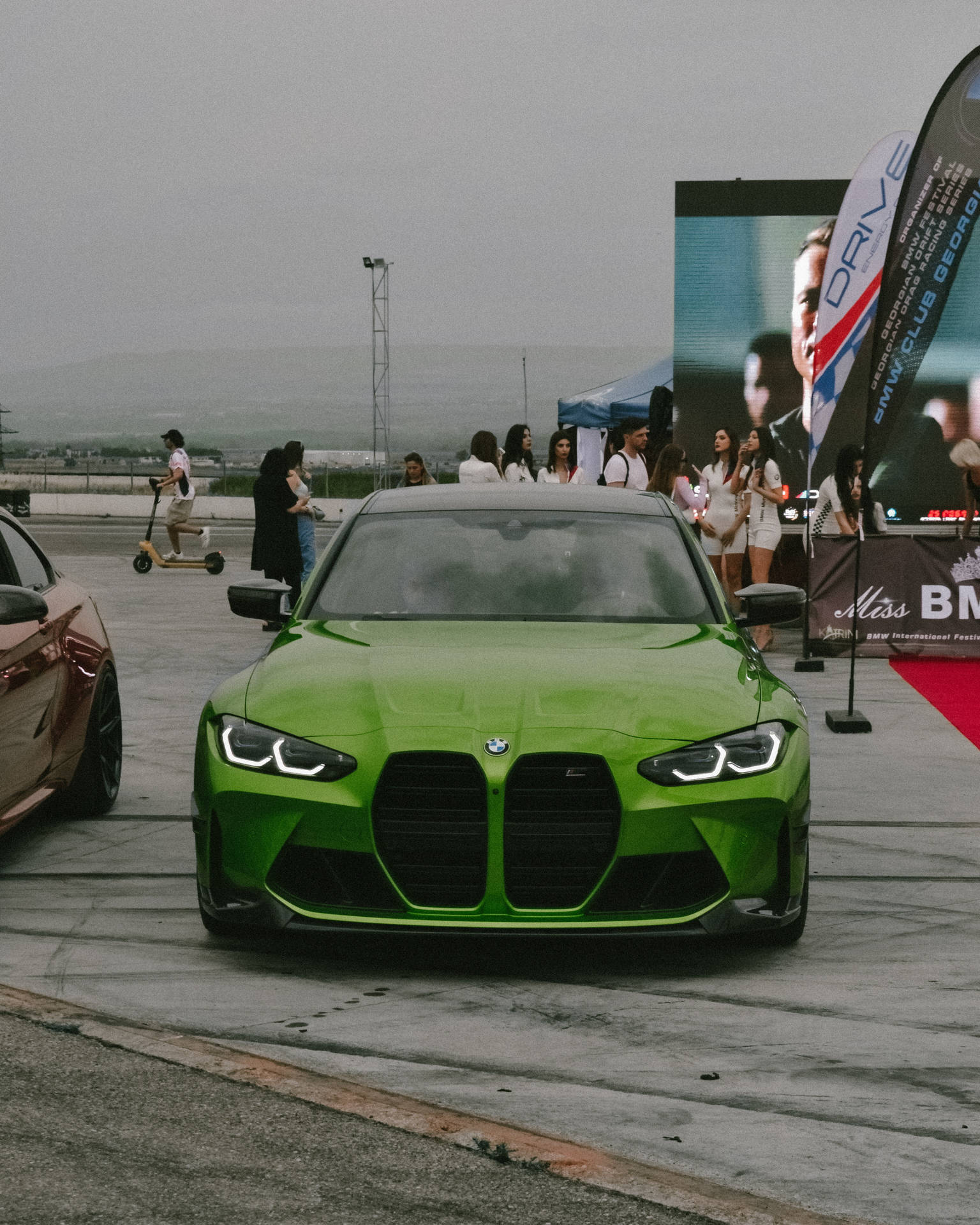 戶外車展中一輛亮綠色BMW M3，附近有參加者。