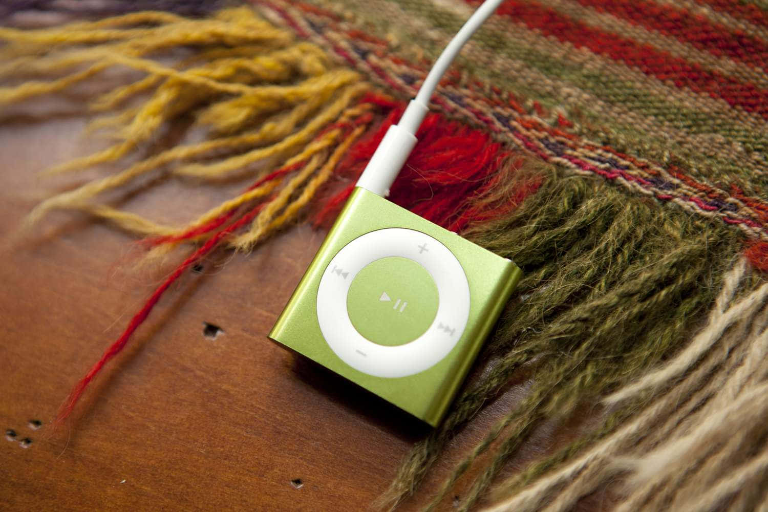 綠色iPod MP3圖片 壁紙 — 一部青檸綠色的 iPod classic 放在木質表面上色彩繽紛的流蘇紡織品上。