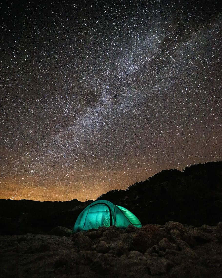 在星空夜空下，一頂發光的綠色帳篷，銀河清晰可見。