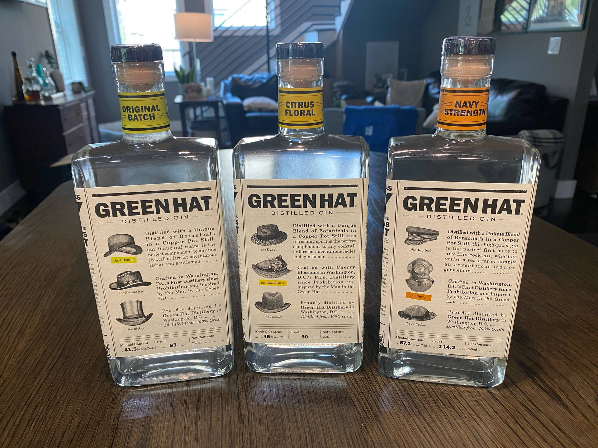 三瓶 Green Hat 氈酒，帶有不同風味標籤，放在木桌上。