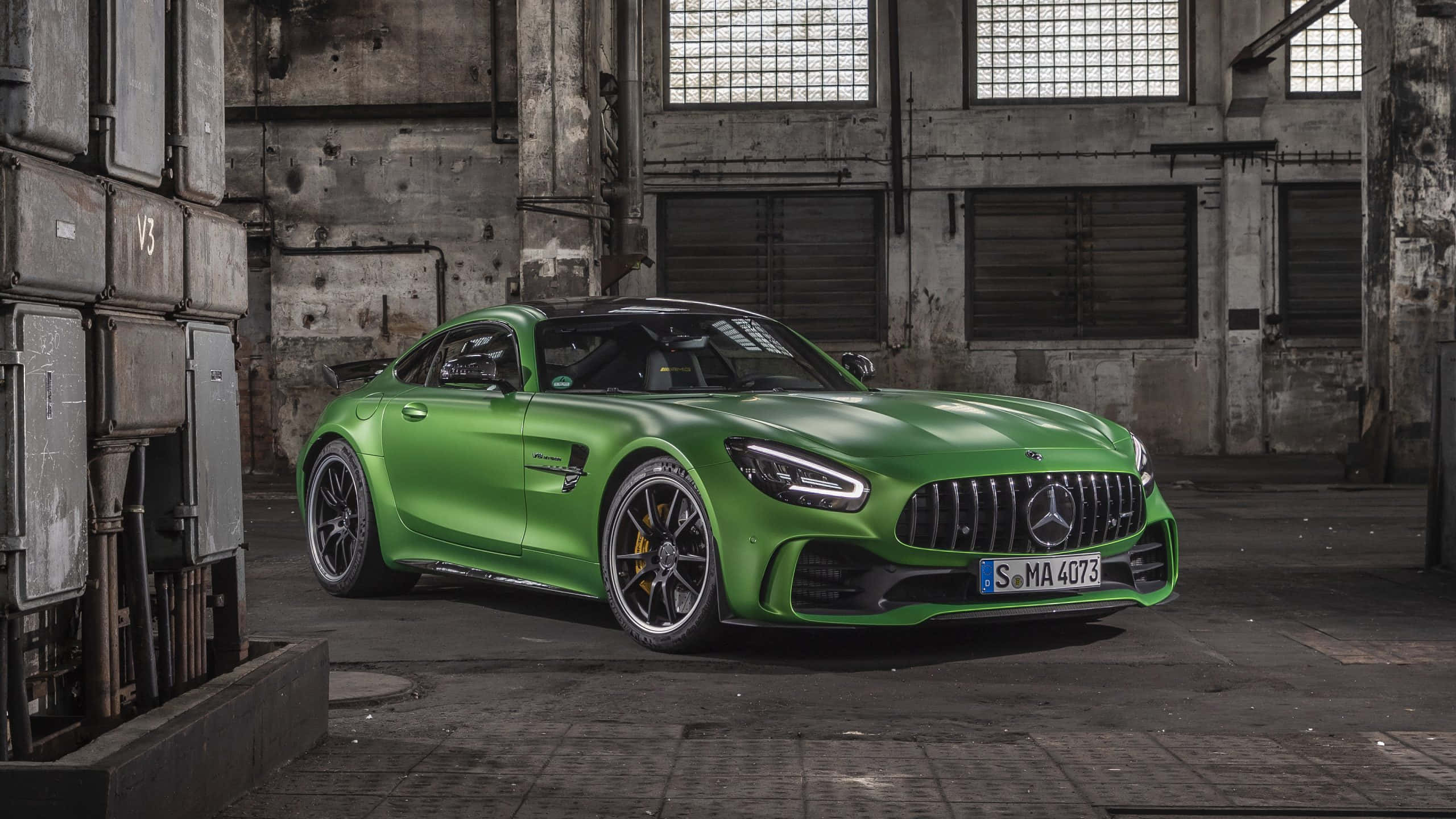 綠色梅賽德斯-AMG GT R 配廢棄建築背景 壁紙 — 一輛充滿活力的綠色Mercedes-AMG GT R跑車在風化的混凝土倉庫內，於工業照明下閃閃發光。